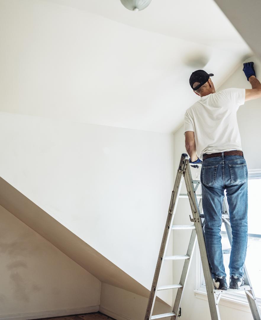Professional painter applying fresh paint to the walls of a modern living room during an interior painting project in Calgary.